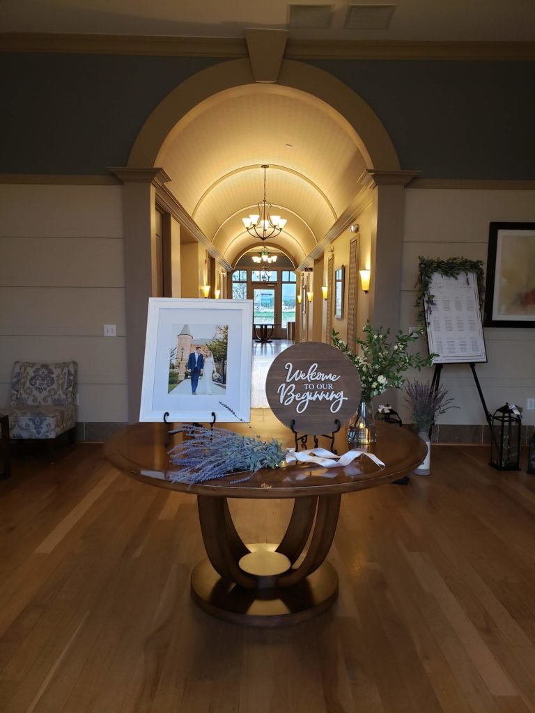 Arched entry hall at Bravo Event Center with a wedding welcome table and engagement photo