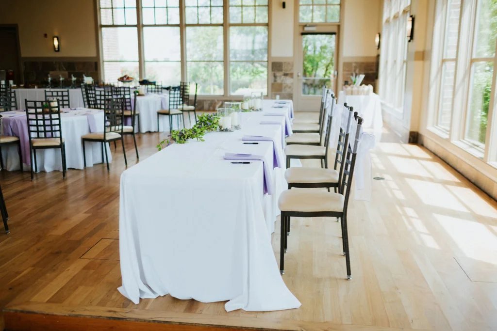 Head table with white linens along the ballroom windows